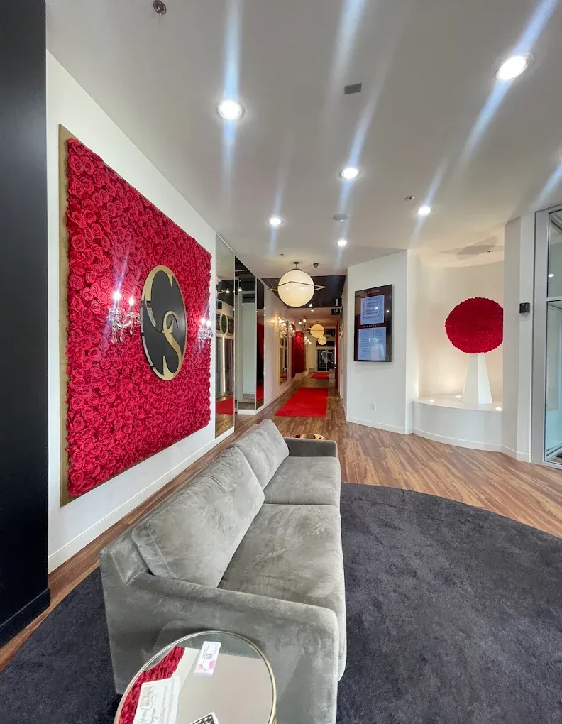 Lobby at Cosmo Salon Studios Canton with a red rose wall, gray sofa and suite hallway