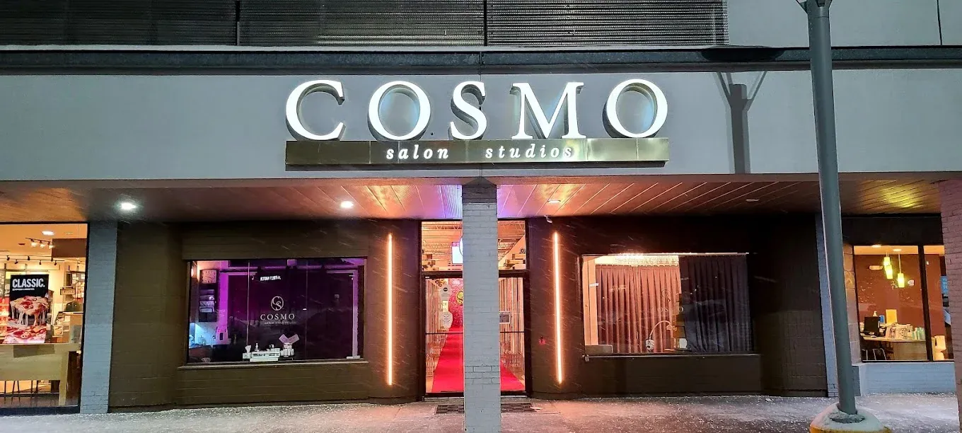 Lit Cosmo Salon Studios sign and storefront at night on Big Beaver Road in Troy